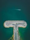 Aerial landscape of small empty artificial peninsula covered with pebbles in bright turquoise bay
