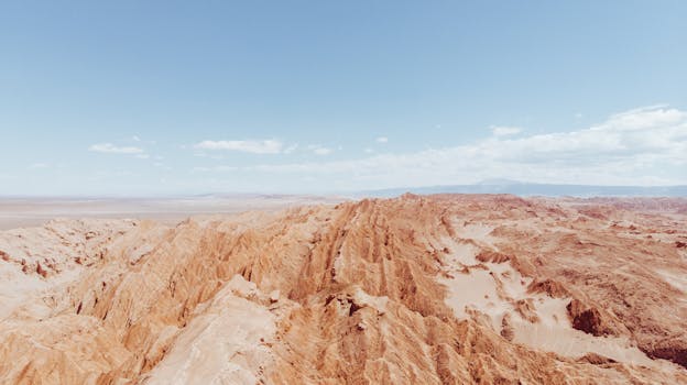 Aerial shot of the rugged terrain in the Atacama Desert, Chile, under a clear blue sky.