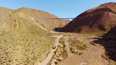 在晴朗的天空下，空中拍摄了阿根廷干旱地区一座横跨干燥山谷的桥梁