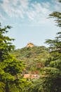 Brown and White House Surrounded by Green Trees Under White Clouds