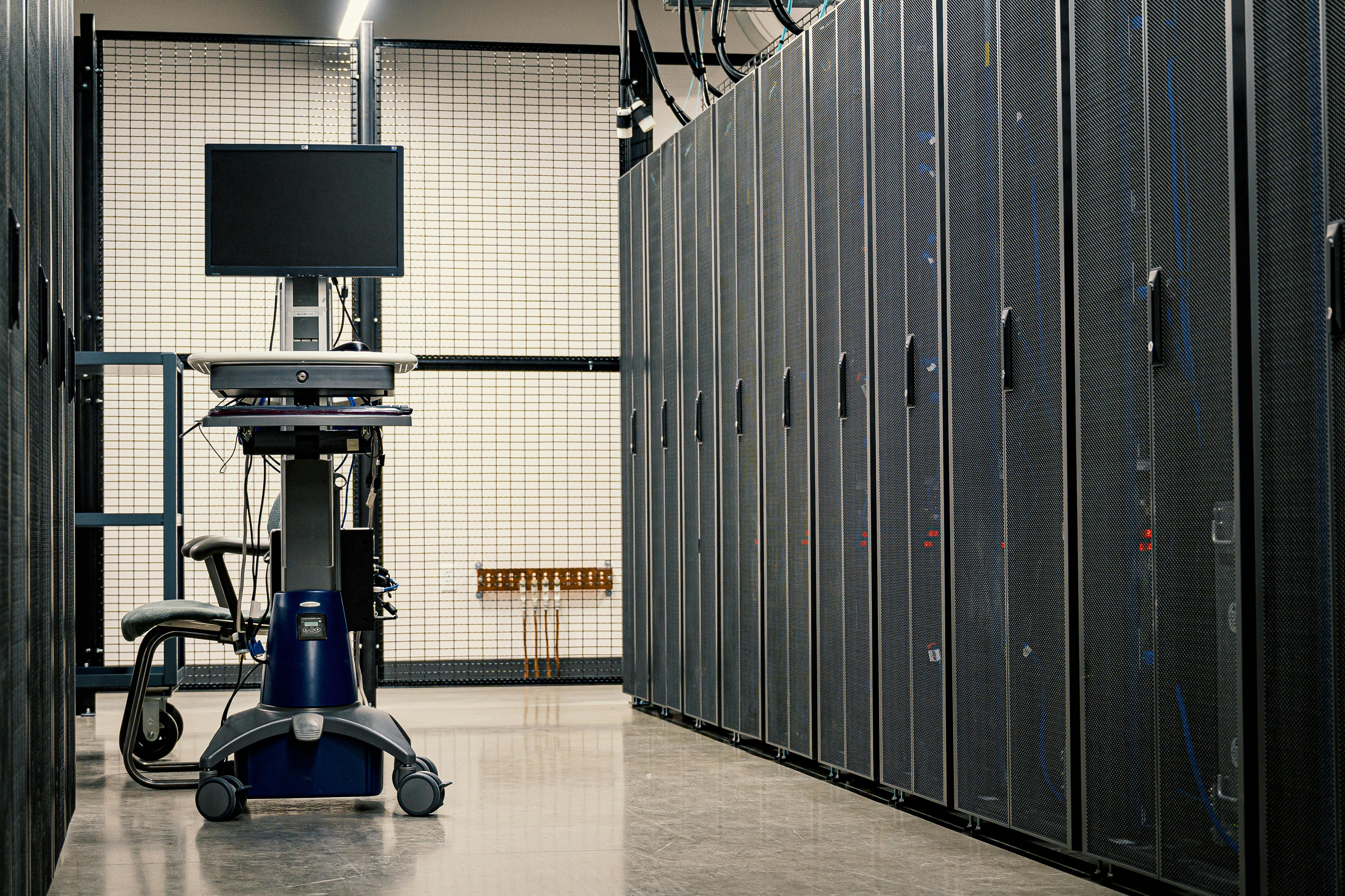 Contemporary computer on support between telecommunication racks and cabinets in modern data center