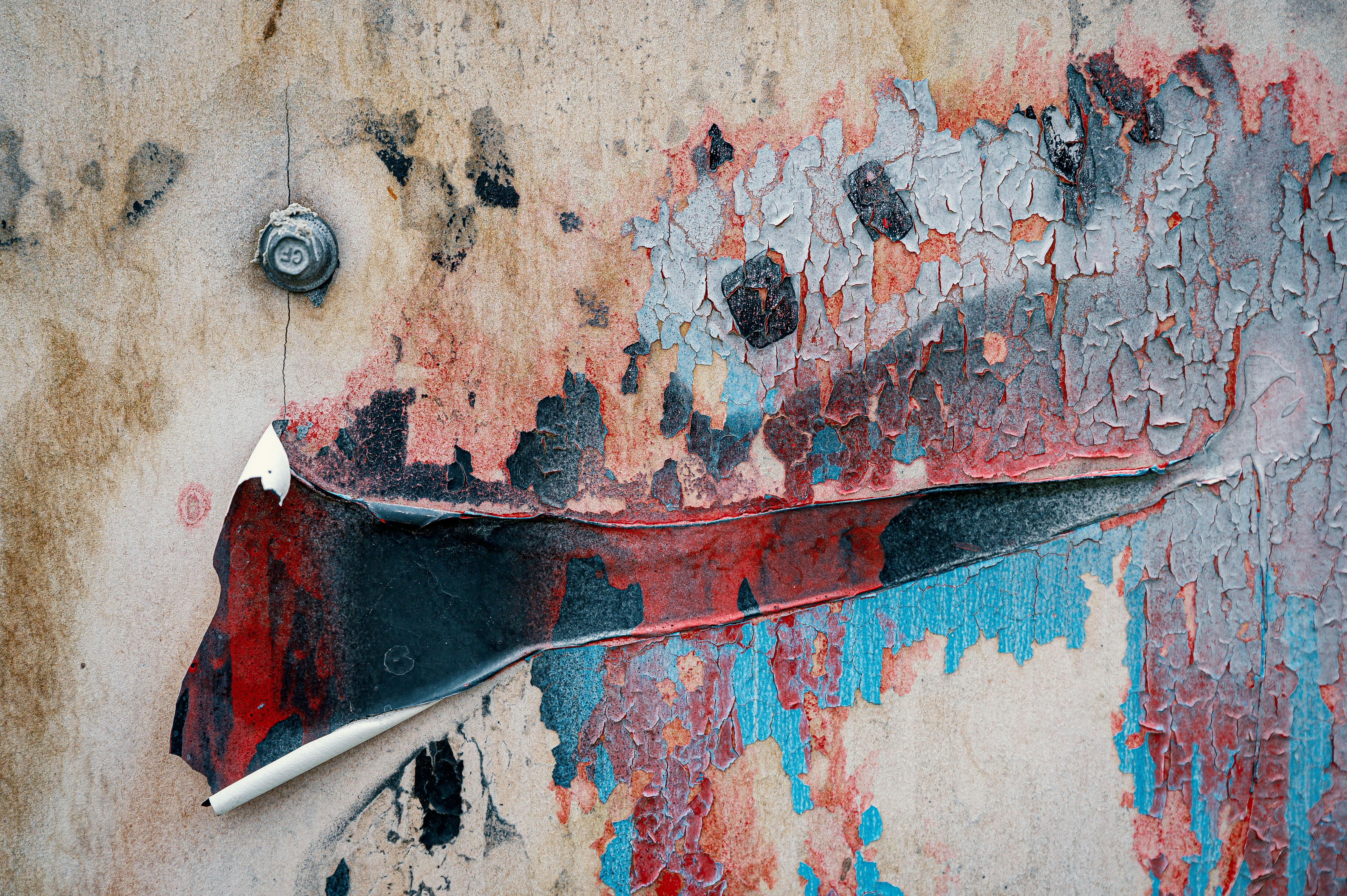 Close-up of a wall showcasing peeling, weathered paint in vibrant colors and grunge textures.