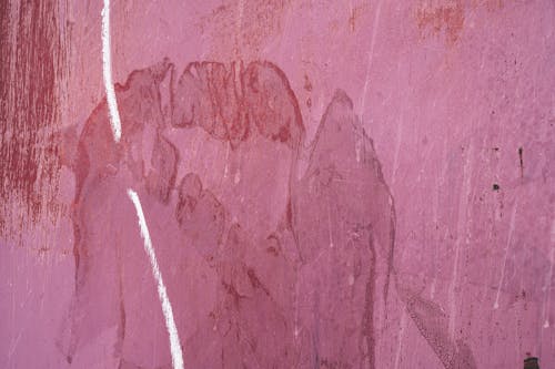 Textured background of pink concrete wall of building with blots and vertical line