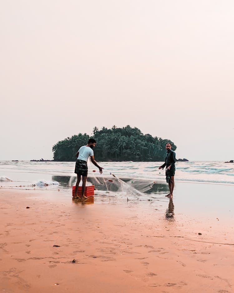 Unrecognizable Indian Fishermen Catching Fish On Sea Shore