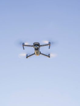 From below of fast unmanned aerial vehicle with propellers and video camera flying in sky