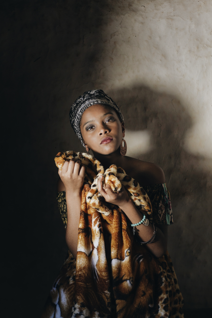 An artistic portrait of a woman holding a patterned blanket, exuding warmth and introspection.