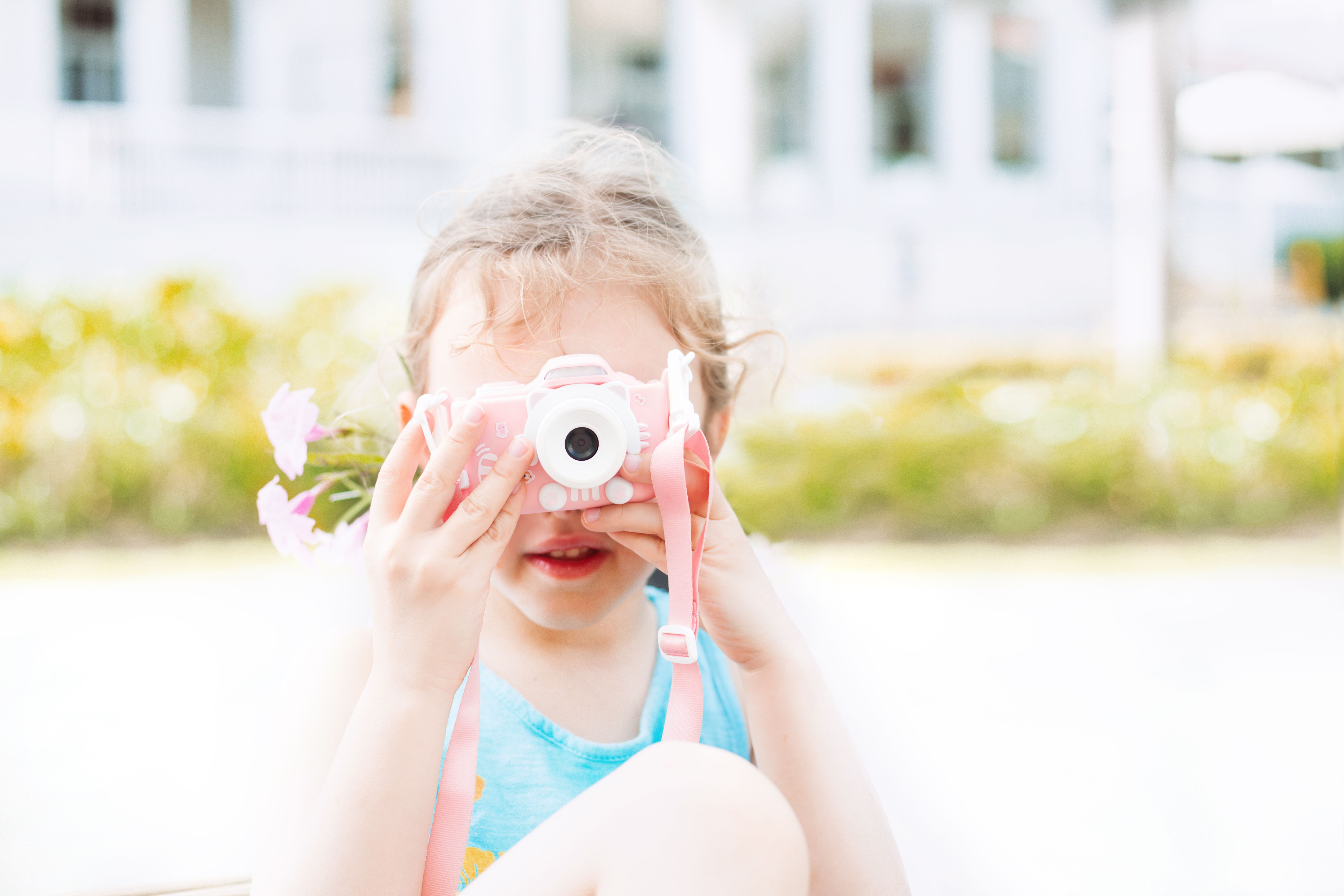 Young girl with toy camera enjoying a sunny day outdoors. Captures childhood play.