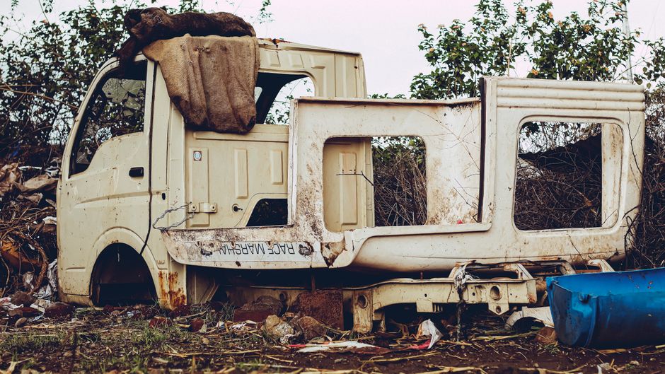 An old, rusty vehicle shell left abandoned in the suburbs of Pune, India.