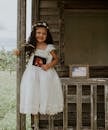 Cheerful child in elegant dress with photo on shabby fence