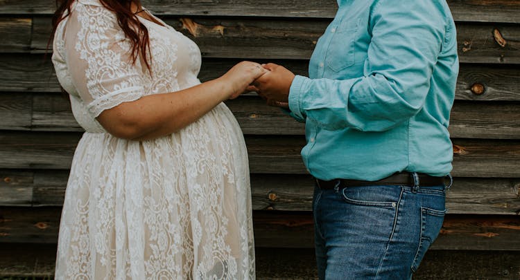 Crop Man Holding Pregnant Woman In Dress By Hand