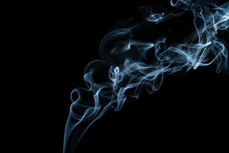 Wavy Smoke Stream On Black Background In Evening