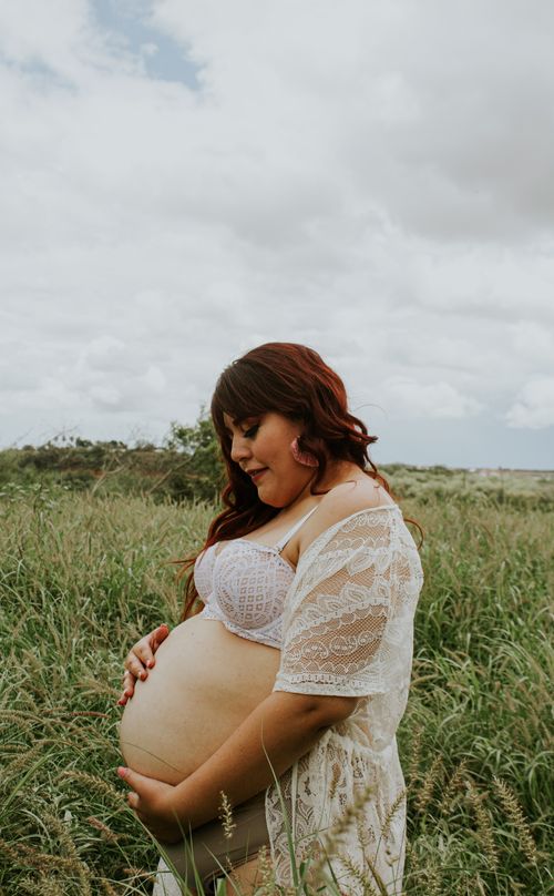 Free Side view of pensive expectant female in lingerie with closed eyes touching tummy in field Stock Photo