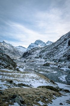 Striking view of snow-capped mountains and a frozen river in a winter wilderness setting.