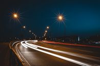 采用长时间曝光拍摄城市道路的弯曲动态夜景，突出灯光轨迹和路灯
