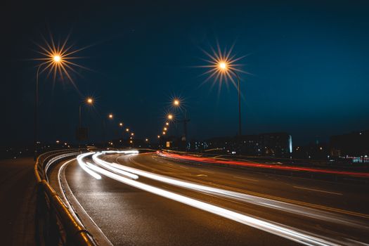 采用长时间曝光拍摄城市道路的弯曲动态夜景，突出灯光轨迹和路灯