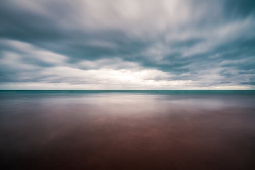 Long exposure wonderful view of peaceful endless sea with turquoise water beneath dramatic cloudy sky