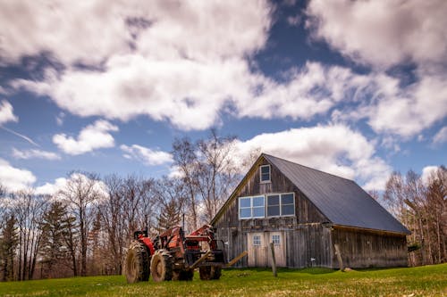 Tractor parked near rural weathered house in countryside