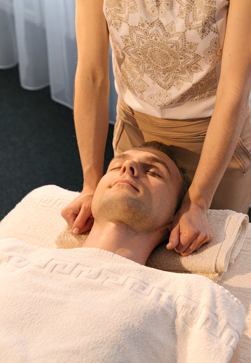 Woman Massaging a Man Lying on Bed