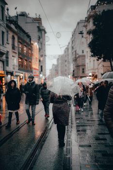 阴雨的城市街道上，一群打着伞的人走在高楼林立的街道上