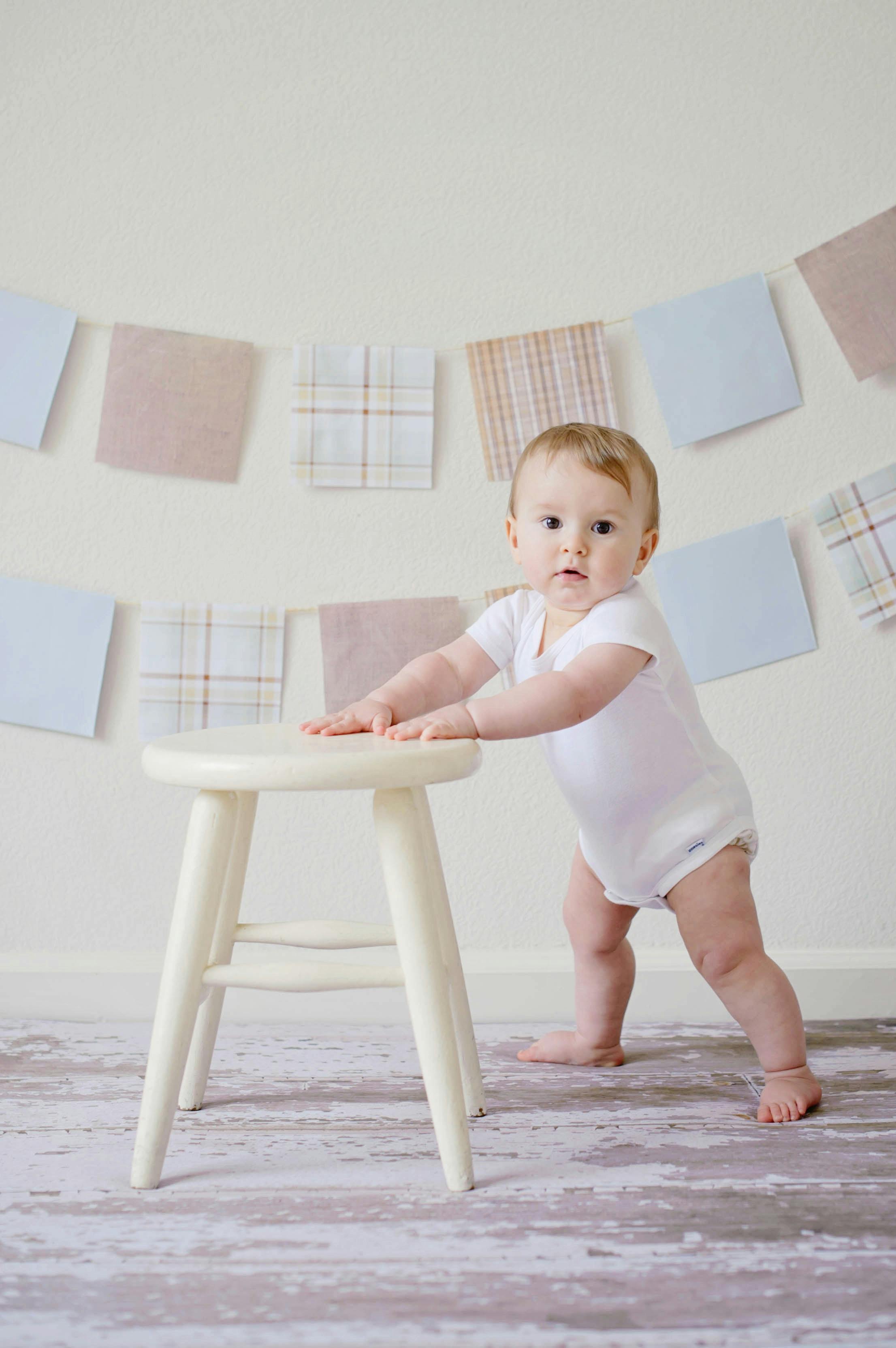 baby holding white wooden stool