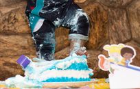 Faceless child pushing festive cake
