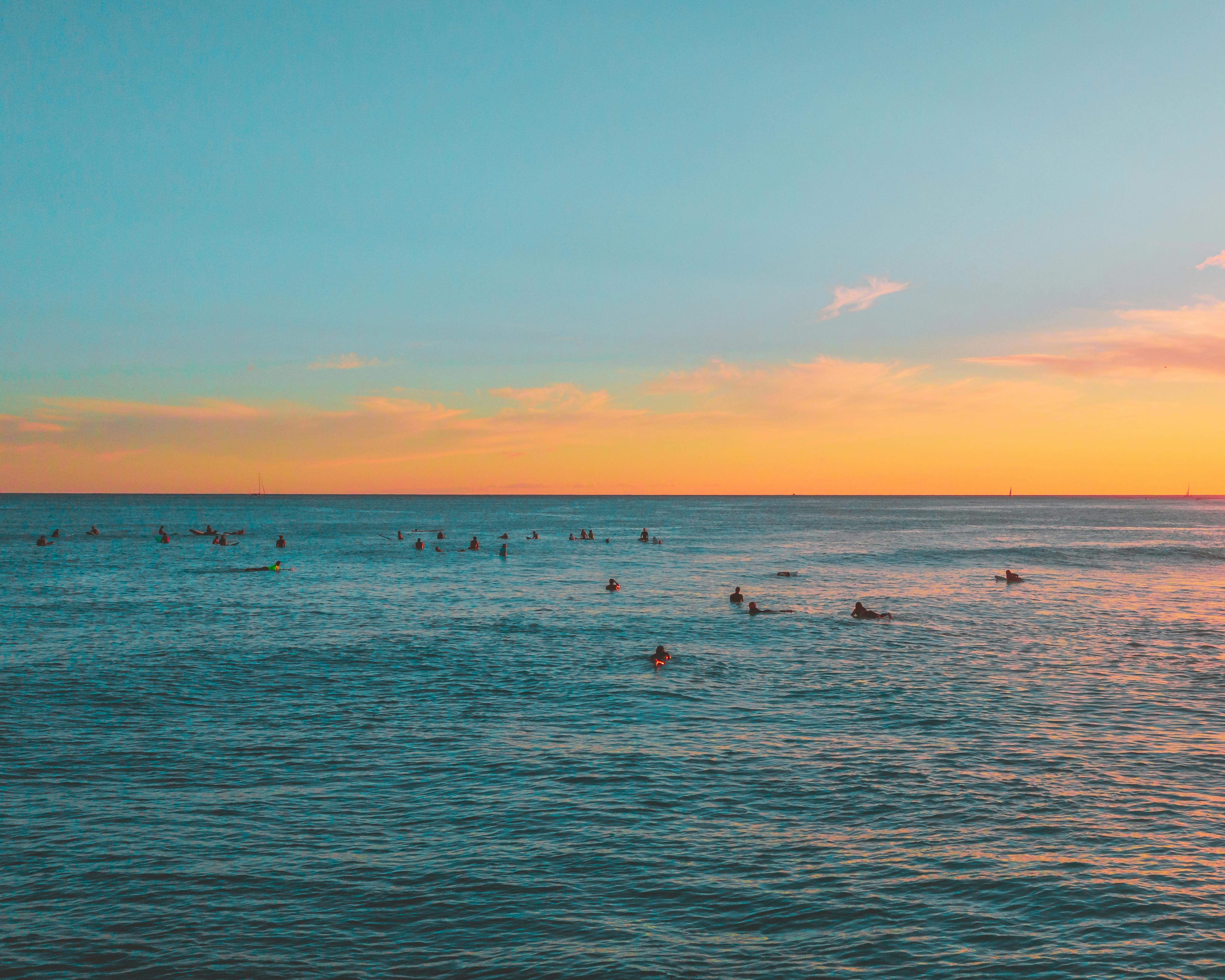 冲浪者沐浴在美丽的夏威夷日落的金色光芒中