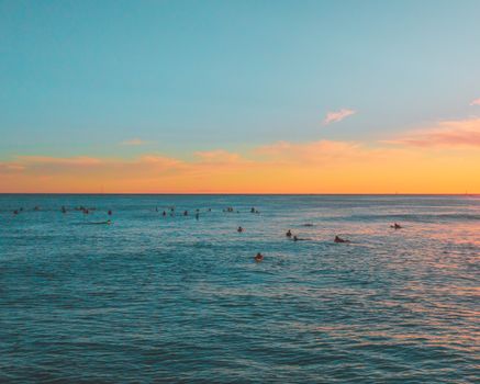 冲浪者沐浴在夏威夷美丽的金色日落光芒中