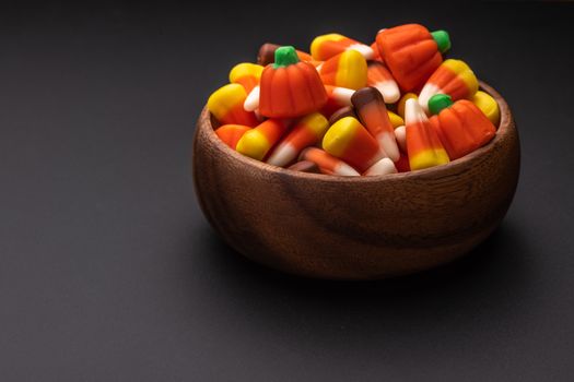 High angle of wooden bowl with sweet marmalade sweets placed on gray surface