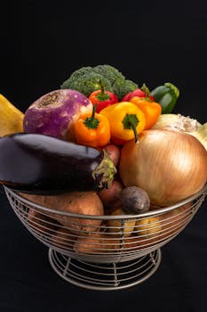 A variety of fresh, organic vegetables in a basket against a black background, perfect for healthy eating concepts.