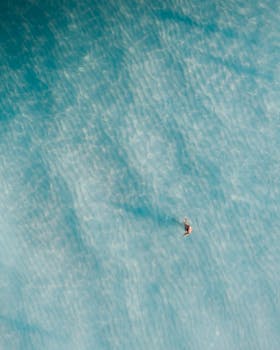 Aerial shot of a solitary swimmer enjoying the clear blue waters of a Hawaiian beach.