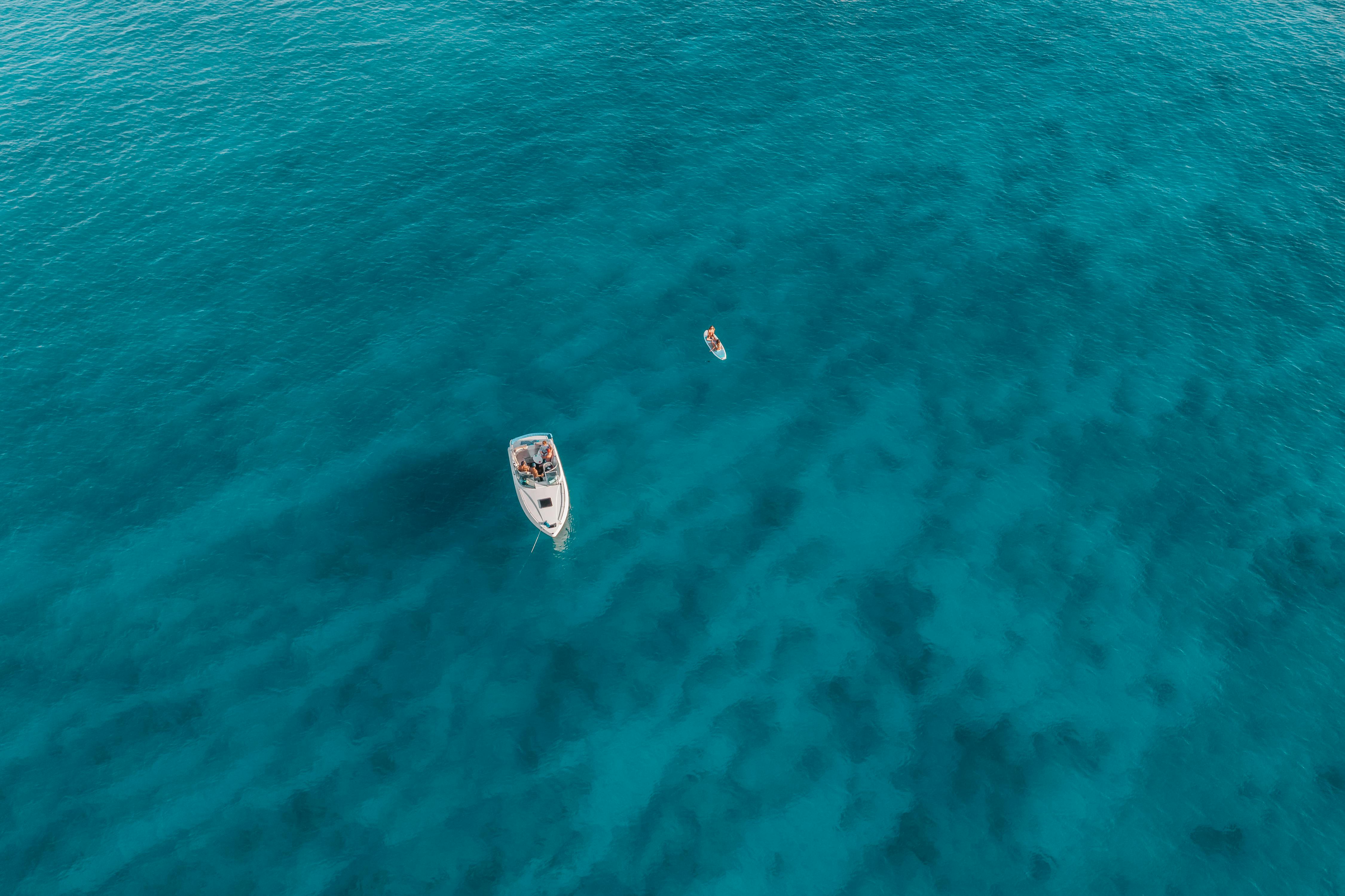 令人惊叹的空中拍摄的船和桨板漂浮在清澈的蓝色夏威夷水域
