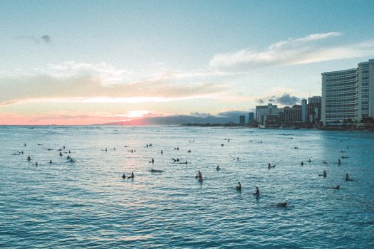 夏威夷海滩上，挤满了享受海浪的冲浪者，日落景色令人惊叹