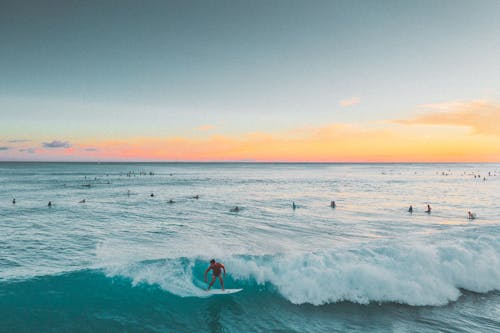 Free Person Surfing on Sea Waves during Sunset Stock Photo