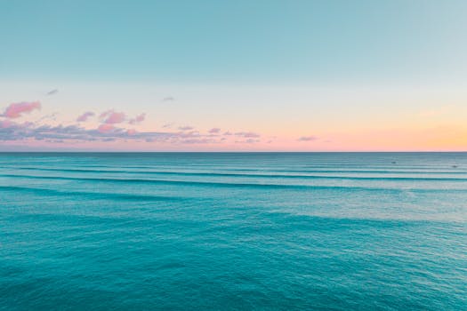 Peaceful ocean view in Hawaii with pastel sunset colors and rippling waves.