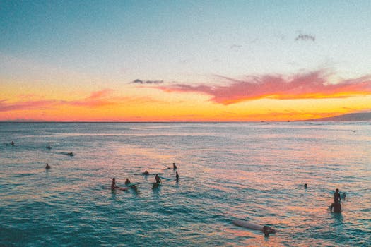Surfers enjoying a vibrant sunset on a Hawaiian beach, showcasing island life and ocean beauty.