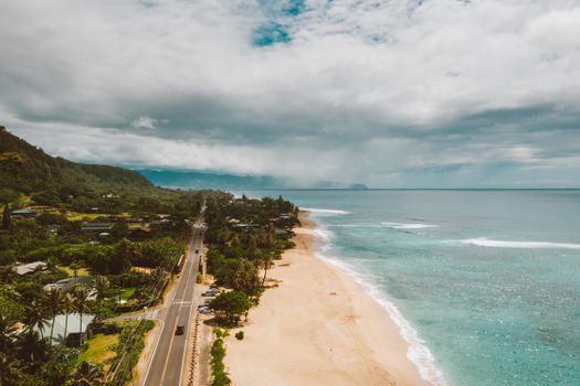 Photo by Jess Loiterton Aerial view of Oahu's stunning coastline with sandy beaches and lush greenery, perfect for tropical travel inspiration.