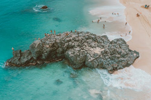 People Surfing on Sea Waves Crashing on Rocky Shore