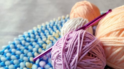Close-up Photo of a Crochet Hook and Colorful Yarns