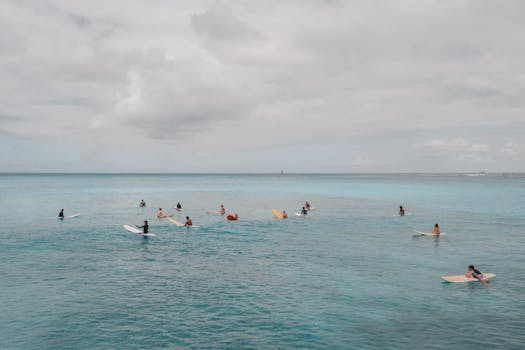 Group of surfers floating on the Pacific Ocean in Hawaii under a cloudy sky.