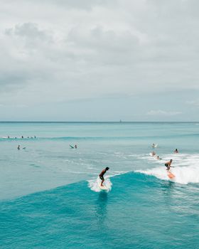 Photo by Jess Loiterton Surfers catching waves off the coast of Hawaii in a stunning aerial drone shot.