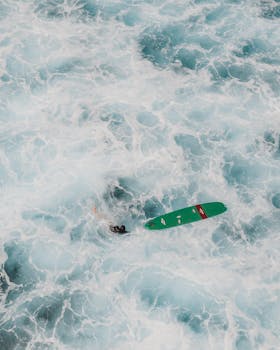 Aerial shot capturing a lone surfer amidst turbulent waves at Pupukea, Hawaii.