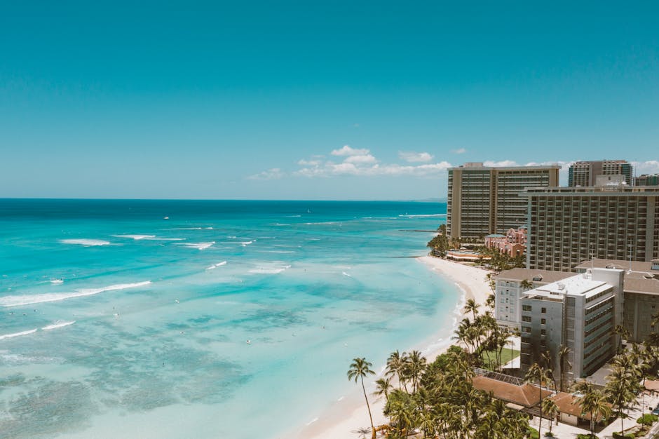 Photo by Jess Loiterton Breathtaking aerial shot of Waikiki Beach and Honolulu's skyline under a clear sky.