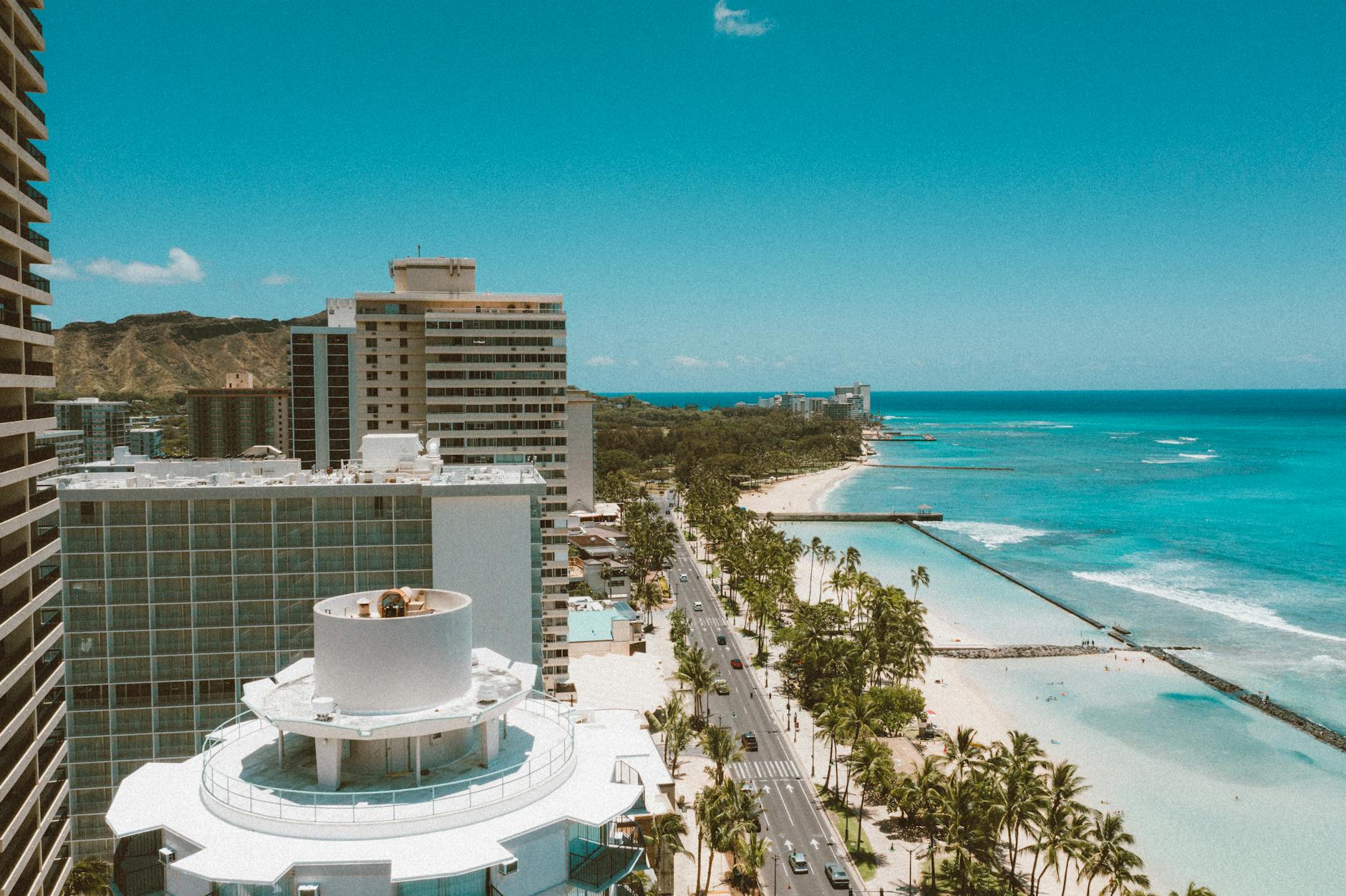 Photo by Jess Loiterton Stunning aerial view of Waikiki Beach with the Honolulu skyline under a bright blue sky.