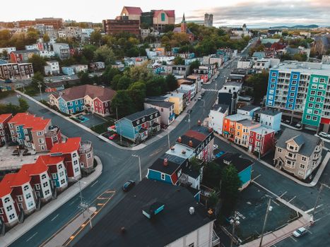 Drone view of bright aged residential building exteriors near asphalt roads in city under cloudy sky
