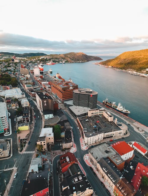 Aerial view of aged house facades with road near ocean and mount under cloudy sky in town