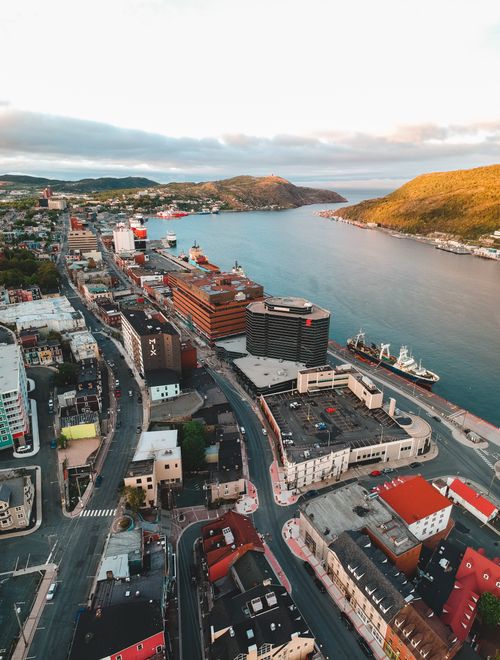 Free Aerial view of aged house facades with road near ocean and mount under cloudy sky in town Stock Photo