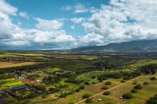 Free Stunning aerial shot of Pupukea countryside with fields, mountains, and cloudy sky. Stock Photo