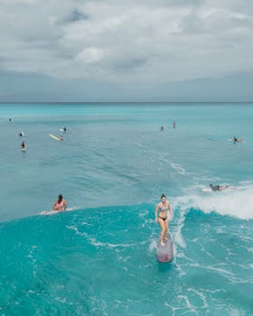 Surfers riding vibrant turquoise waves off the coast of Honolulu, capturing the essence of a sunny beach day.