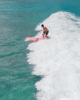 Surfer skillfully rides a wave on a clear day, captured from above.