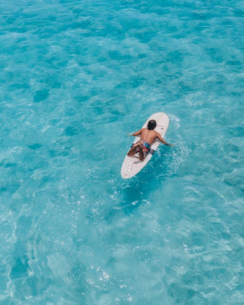 Woman in White and Pink Bikini Top and Blue Denim Daisy Dukes on White Surfboard in on on on on